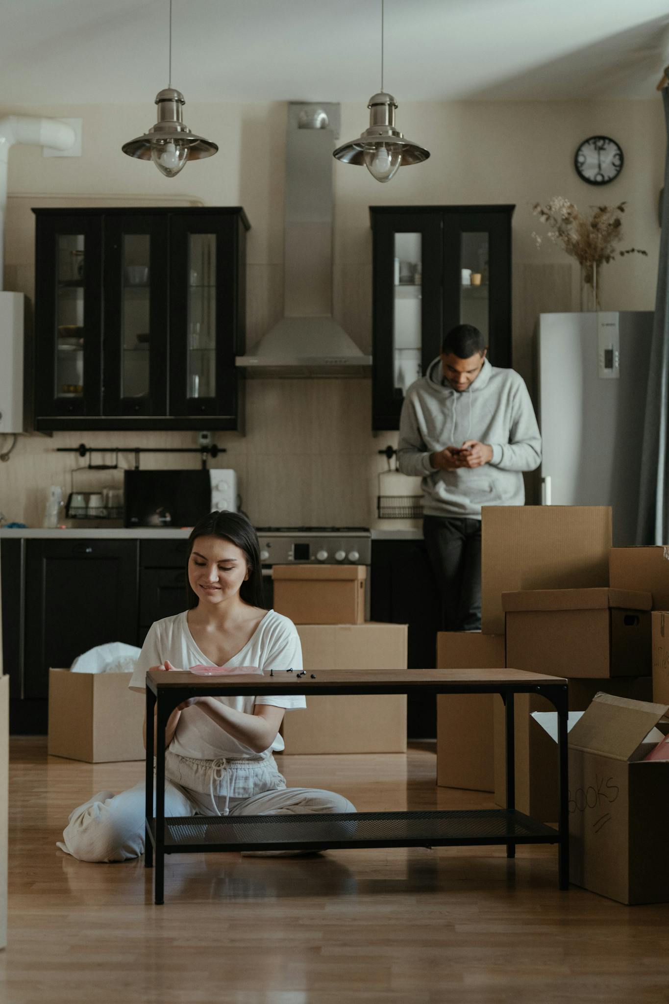 A couple assembling furniture in their new home's kitchen amidst moving boxes.
