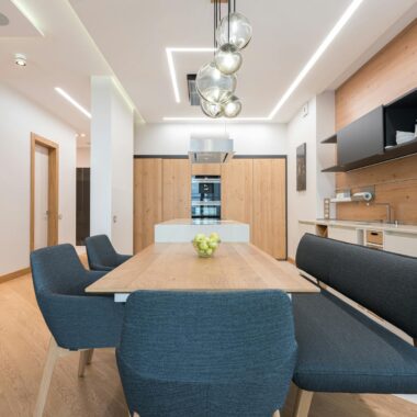 Dining zone with wooden table and soft chair and cushion placed in modern kitchen of spacious apartment