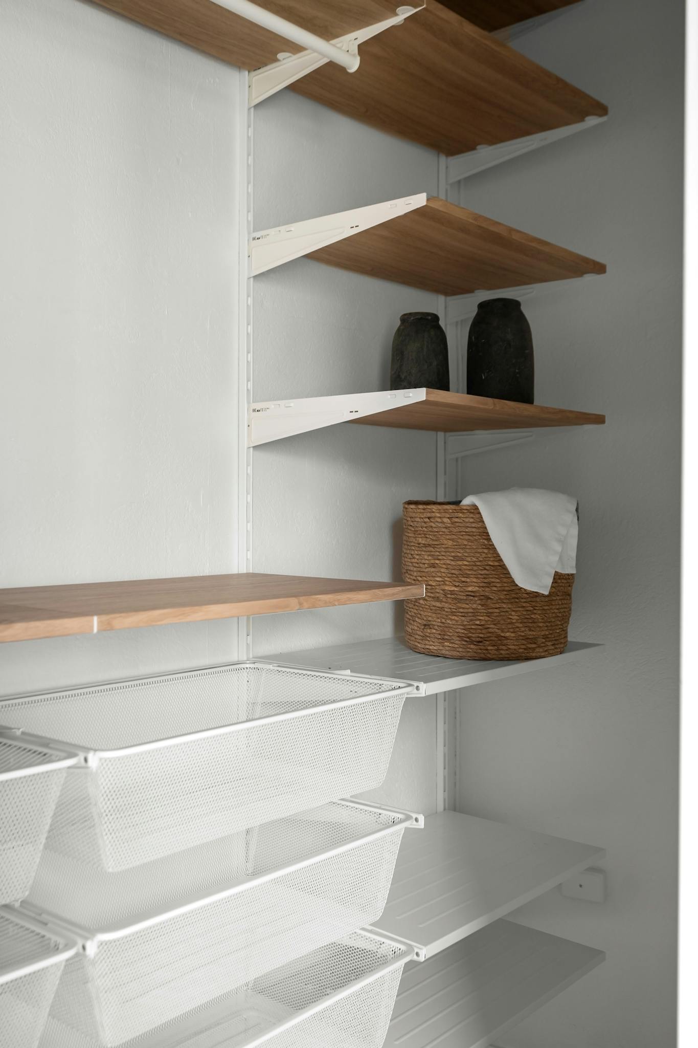 Elegant modern closet with wood and metal shelving, perfect for minimalist storage solutions.