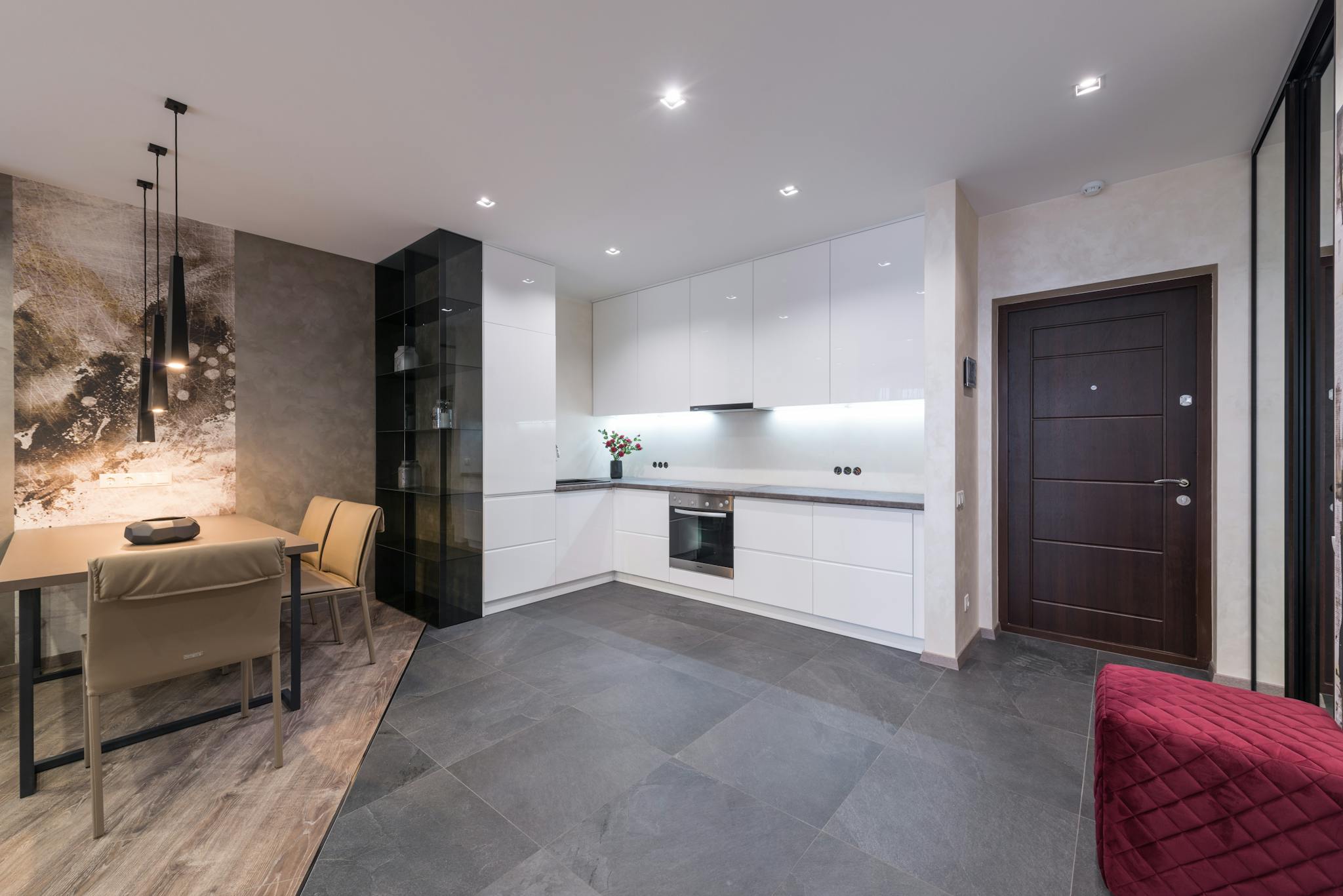 Sleek and contemporary kitchen interior with white cabinets and dining area.
